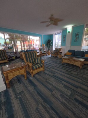 A spacious room with striped carpeting, wicker furniture, and a ceiling fan. - Oceanfront Paradise at Fountain Beach Resort / Daytona Beach (Daytona Beach)