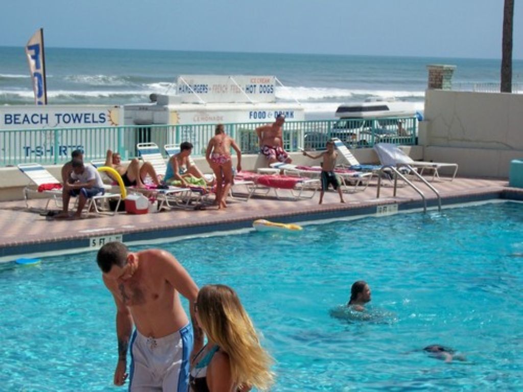 Een zwembadgedeelte met ligbedden en een bord voor strandhanddoeken en horeca.