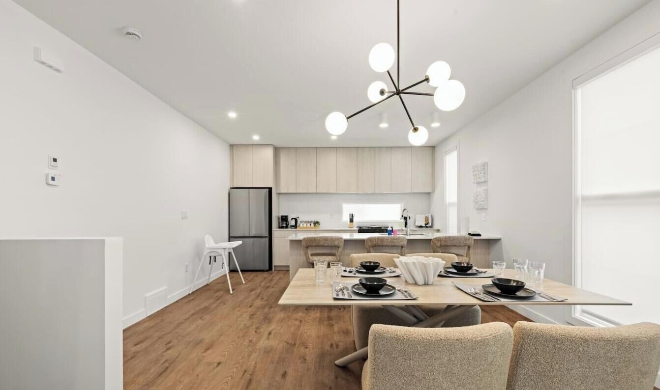 A modern kitchen with a central island, white cabinetry, and a hanging light fixture.