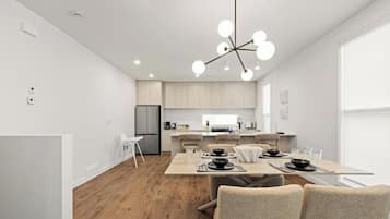 A modern kitchen with a central island, white cabinetry, and a hanging light fixture.