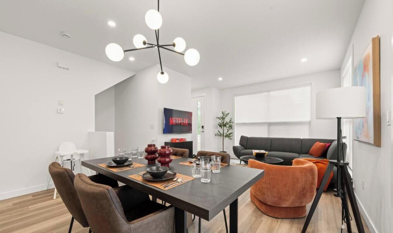 A modern living space with a dining area, a sofa, a lamp, and a television.
