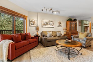 A living room with a red sofa, a brown sofa, a patterned armchair, a wooden coffee table, and artwork on the walls. - Scenic Mountain Sanctuary Steps from Keystone Gondola (Keystone)