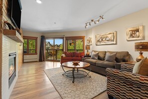 A spacious living room with a fireplace, a sofa, a coffee table, and a view of the outside. - Scenic Mountain Sanctuary Steps from Keystone Gondola (Keystone)