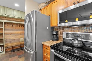 A kitchen with a stainless steel refrigerator, a coffee maker, a kettle, and wooden cabinets. - Scenic Mountain Sanctuary Steps from Keystone Gondola (Keystone)