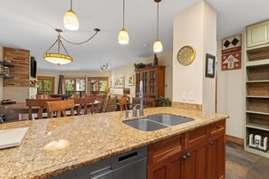 A kitchen with granite countertops, a dishwasher, wooden cabinets, and pendant lighting. - Scenic Mountain Sanctuary Steps from Keystone Gondola (Keystone)