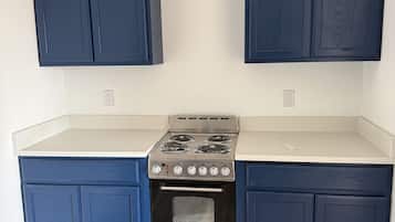 A kitchen with dark blue cabinets, a stainless steel stove, and a white countertop.
