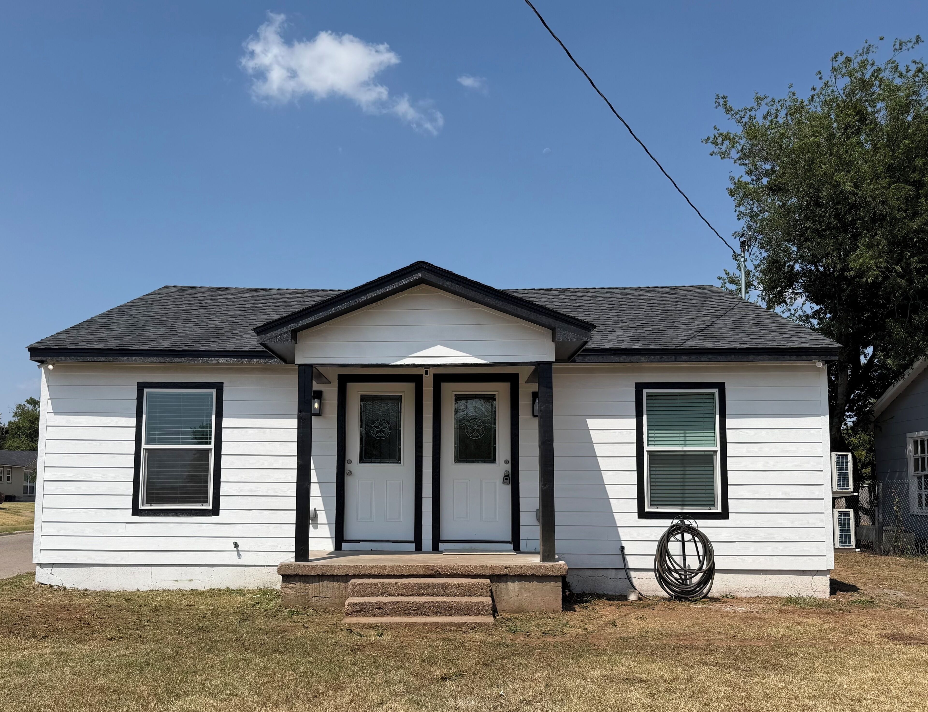 A single-story house with a gabled roof, a front porch, and a small front yard.