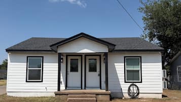 A single-story house with a gabled roof, a front porch, and a small front yard.
