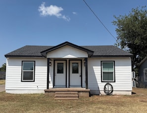 A single-story house with a gabled roof, a front porch, and a small front yard.