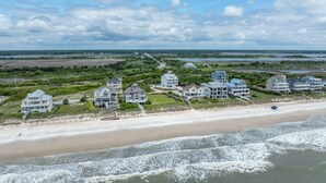 A coastal residential area with beachfront properties featuring multiple stories, balconies, and a boardwalk leading to the beach. - Poolside retreat for large groups (North Topsail Beach)