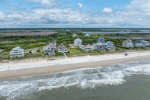 Eine Wohngegend an der Küste mit Strandhäusern, mehreren Stockwerken und Balkonen, verbunden durch eine Promenade, die zum Strand führt.