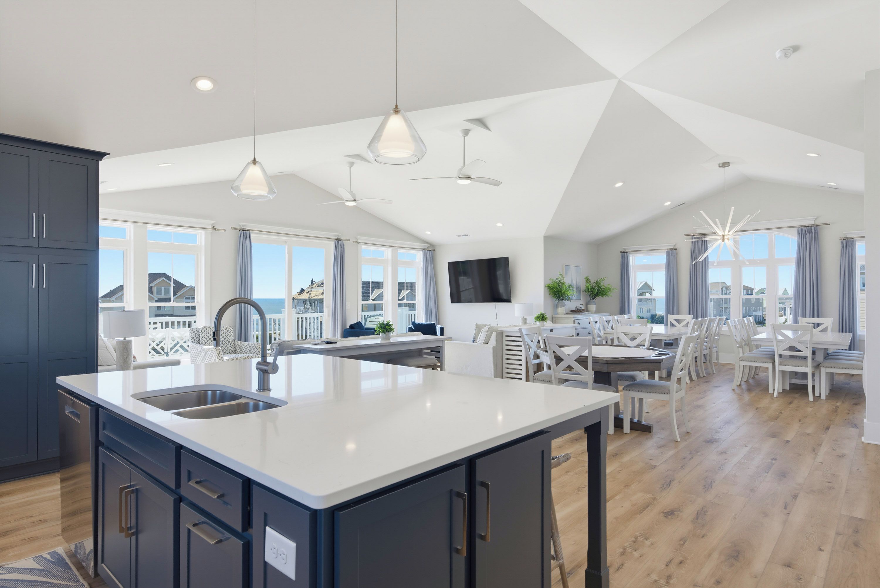 A spacious kitchen with a large island, modern pendant lights, and a dining area with white furniture.