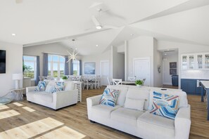 A spacious living area with a high ceiling, a dining area with a view, and a kitchen with cabinets. - Poolside retreat for large groups (North Topsail Beach)
