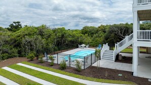 A residential property with a swimming pool, a covered patio, and a staircase leading to an upper level. - Poolside retreat for large groups (North Topsail Beach)