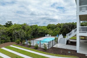 Ein Wohnhaus mit Swimmingpool, überdachter Terrasse und einer Treppe, die zu einer oberen Ebene führt.