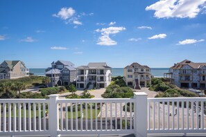 A beachfront property with multiple buildings, a clear sky, and a view of the ocean. - Poolside retreat for large groups (North Topsail Beach)
