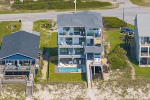 A multi-story beachfront property with a swimming pool, multiple balconies, and a wooden deck. - Oceanfront pool retreat for large groups (North Topsail Beach)