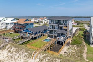 A coastal residential area with multiple houses, a swimming pool, and a beach access walkway. - Oceanfront pool retreat for large groups (North Topsail Beach)