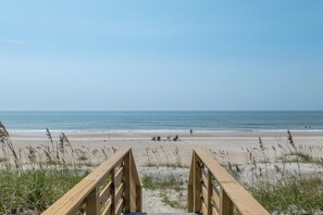 A wooden boardwalk leading to a beach with a clear view of the ocean and people in the distance. - Oceanfront pool retreat for large groups (North Topsail Beach)