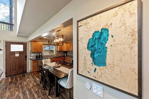 A kitchen with wooden cabinets, a dining table, and a large map on the wall. - Heavenly Tahoe Escape: EV Charger, BBQ, Balcony (South Lake Tahoe)