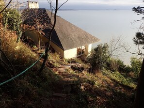 A house with a sloped roof overlooking a body of water. - Charming 2-bedroom house  face the sea,  magical stay in calm nature (Champeaux)