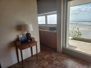 Une pièce avec une table en bois, une lampe et une fenêtre donnant sur la plage.
