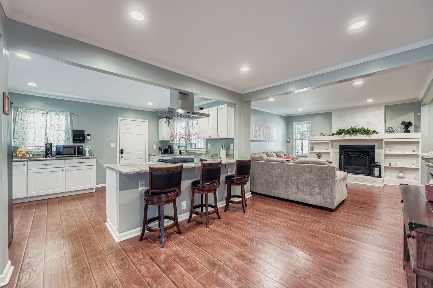 A modern kitchen with a central island, bar stools, and a fireplace.