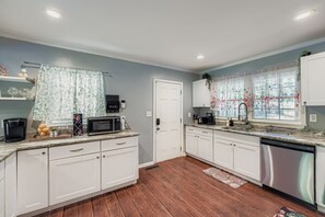 A modern kitchen with white cabinets, a microwave, a coffee maker, and a sink. - Experience Modern Comfort at The Pink Magnolia House (Decatur)