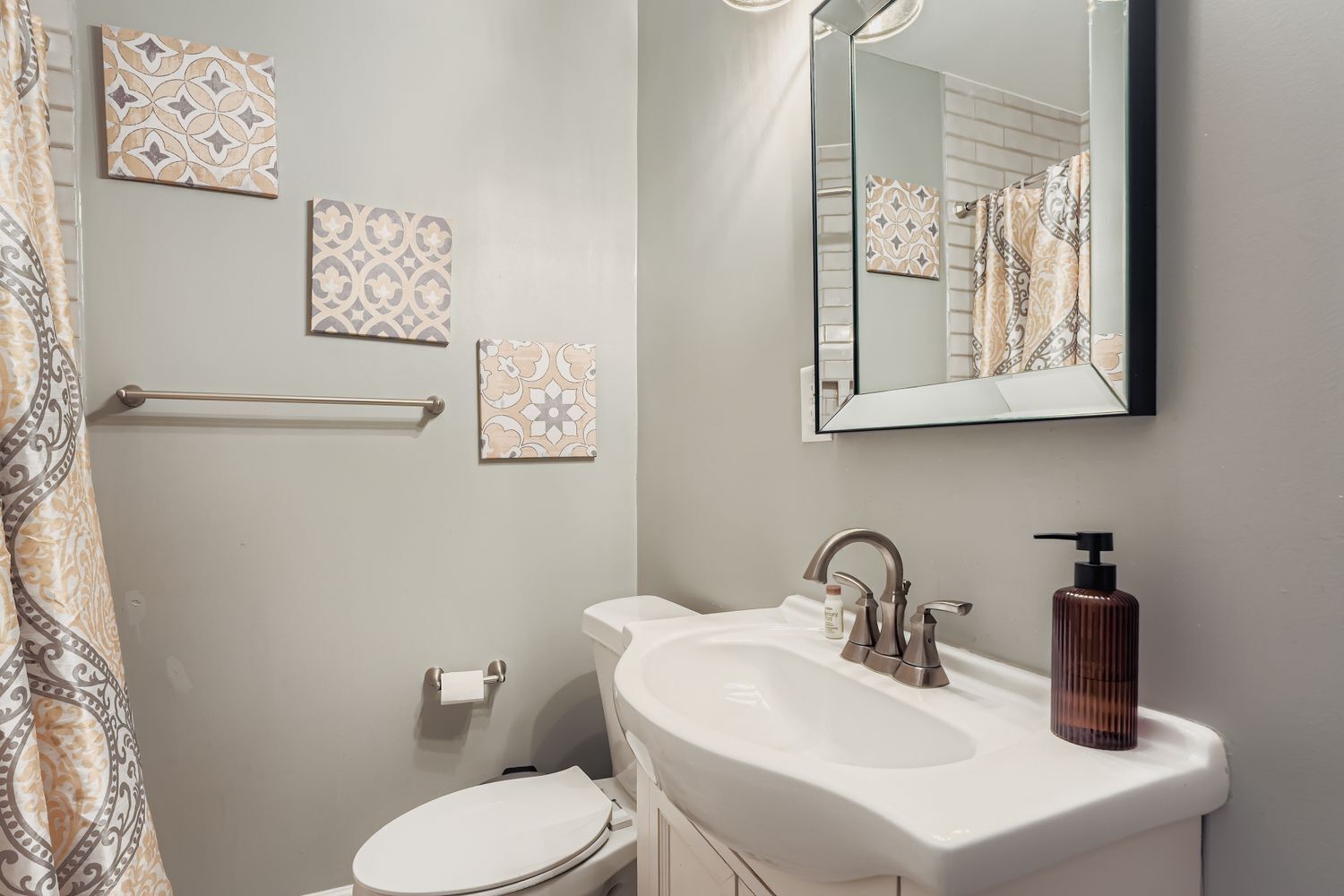 A bathroom with a white sink, a mirror, and patterned wall tiles.