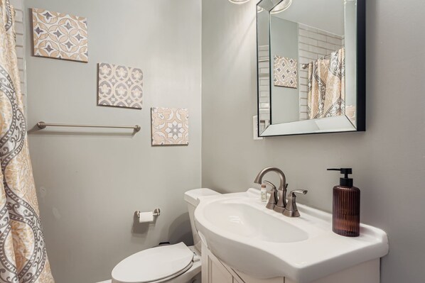 Un baño con lavamanos blanco, un espejo y azulejos con diseño.