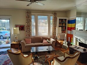 Ein Wohnzimmer mit Sofa, Couchtisch, Sesseln, Kamin, Bücherregal und einer Flagge.