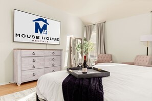 A bedroom with a bed, a dresser, a mirror, a window with curtains, and a sign for 'Mouse House Rentals'. - Family Fun, Heated Pool, Slide, Hot Tub, Game Room (San Antonio)