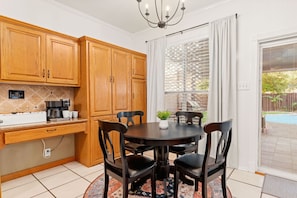 A kitchen with wooden cabinets, a coffee maker, and a dining table with chairs. - Family Fun, Heated Pool, Slide, Hot Tub, Game Room (San Antonio)