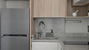 A modern kitchen with a stainless steel refrigerator, a granite countertop, a built-in sink with a faucet, and wooden cabinets. - Leafy Sunlight Lock up and Go | Green Point (Cape Town)