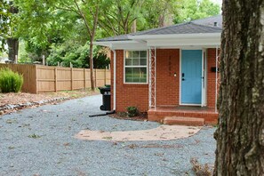 A residential house with a blue door, a front porch, and a gravel driveway. - Serene 2BR + Study, Min to NoDa & Uptown (Charlotte)