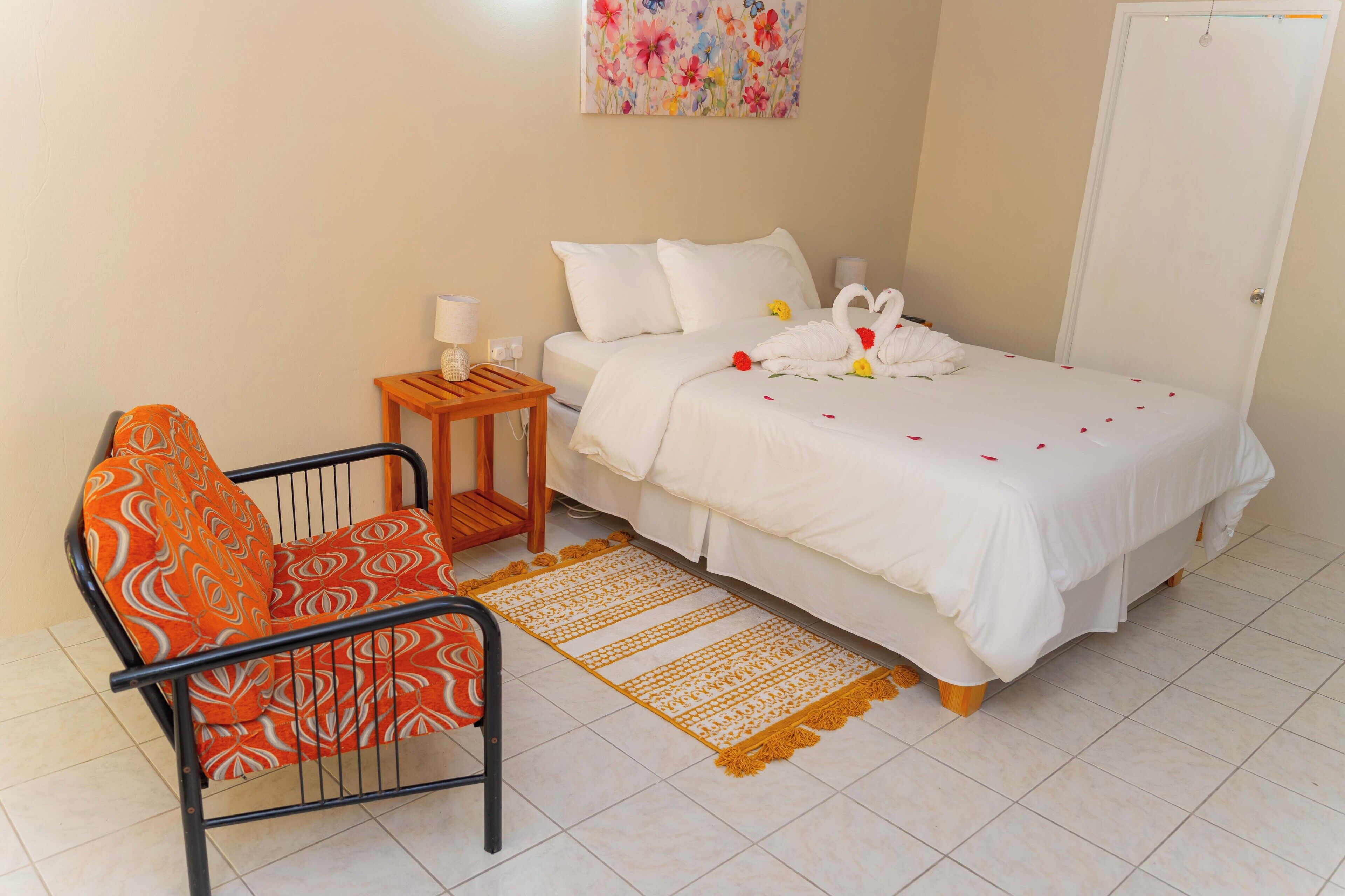 A hotel room with a bed, a chair, a nightstand, and a wall decoration.