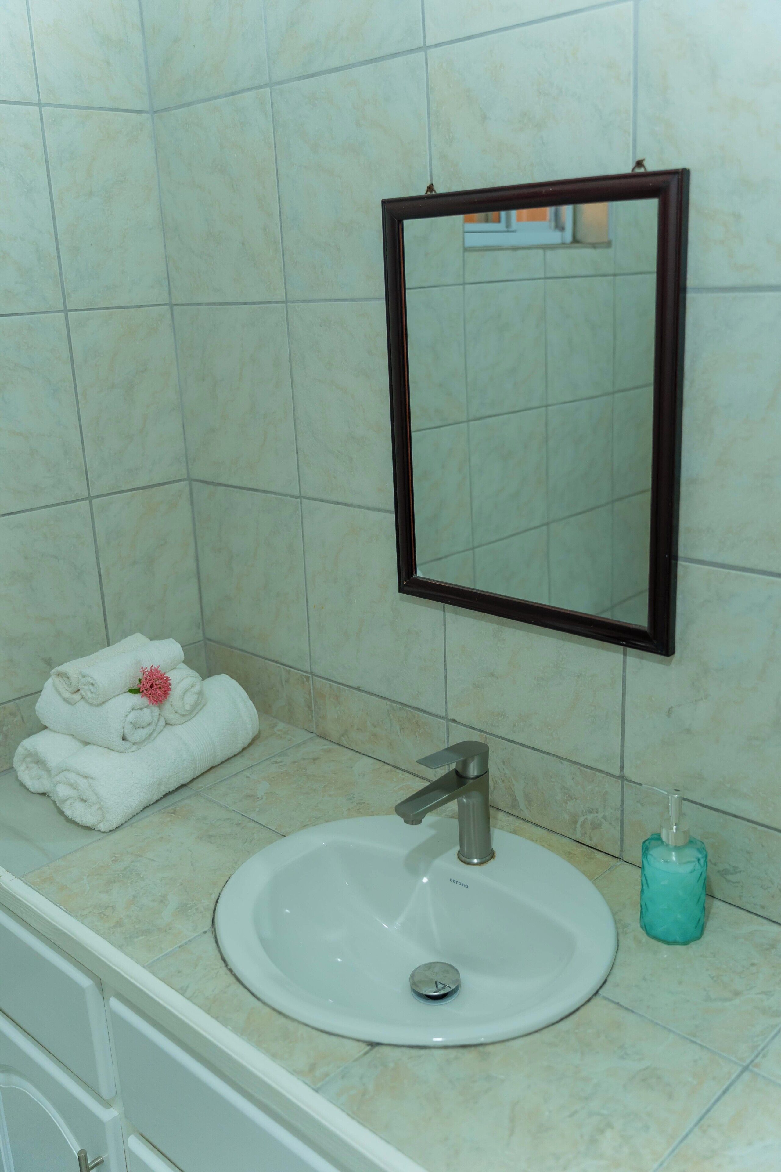 A bathroom with a white sink, a mirror, and a towel rack with folded towels.
