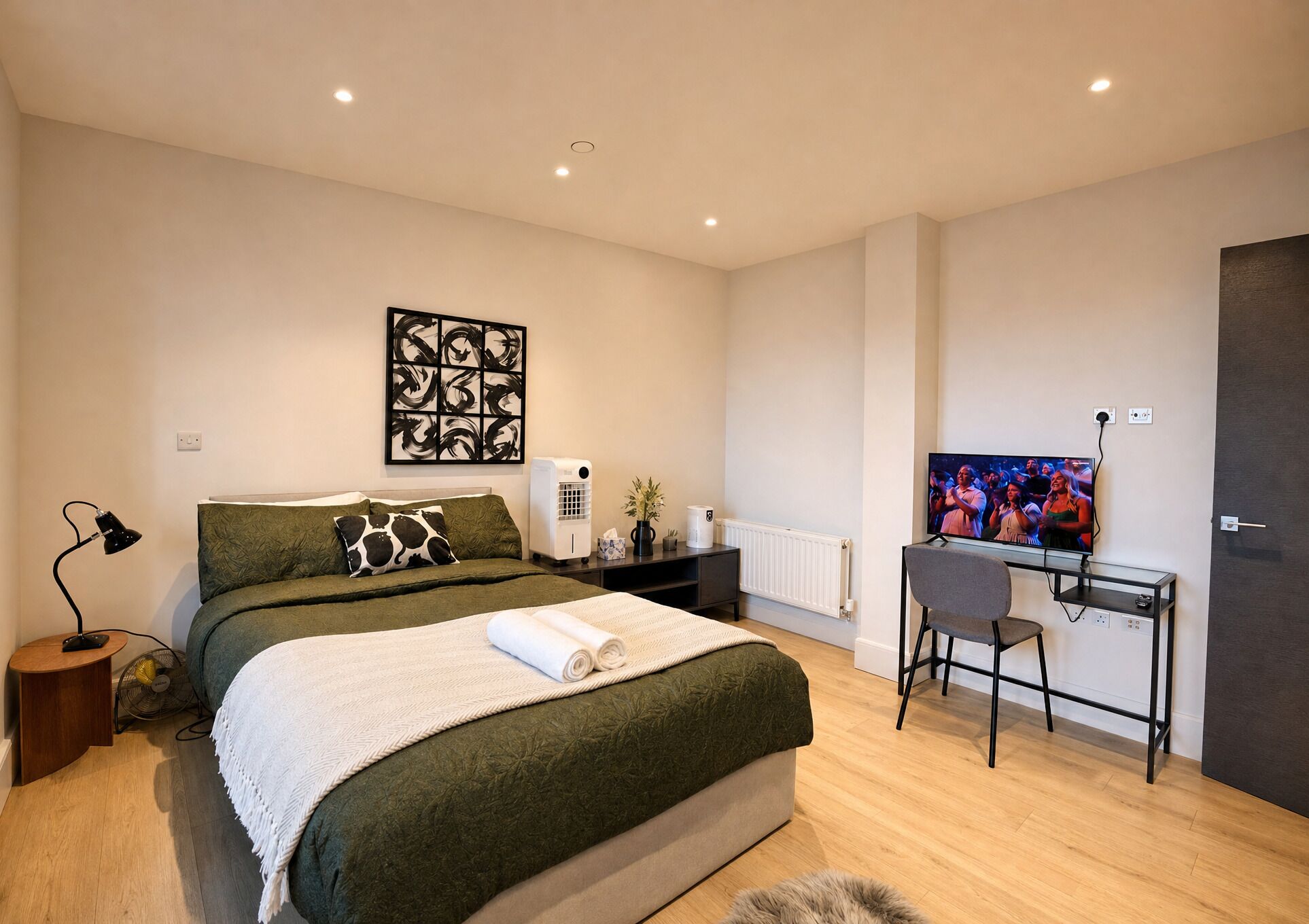 A modern bedroom with a bed, a desk, and a television.