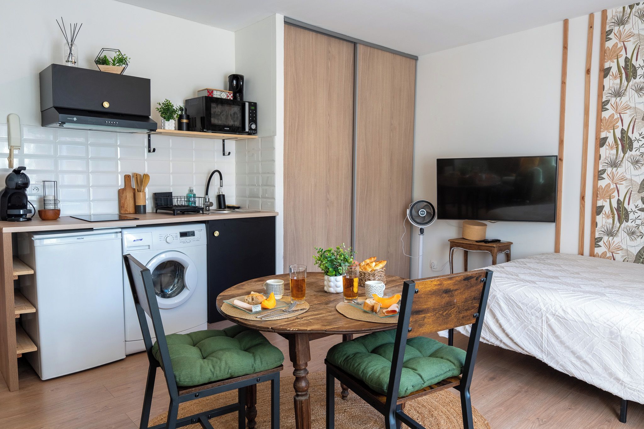 A compact living space with a kitchenette, a dining area, and a bed.