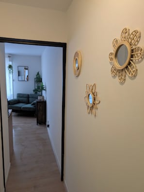 Un pasillo con un sofá y un espejo al fondo, además de dos espejos decorados con un diseño floral.