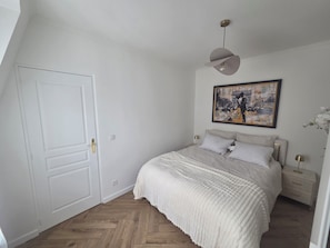 A bedroom with a bed, a door, a painting, and a nightstand. - Beautiful 1-bedroom apartment in Paris perfect for your getaway (Paris)