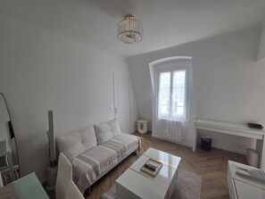A modern living room with a sofa, a coffee table, a TV, and a desk. - Beautiful 1-bedroom apartment in Paris perfect for your getaway (Paris)