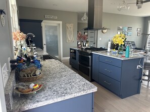 A modern kitchen with granite countertops, a built-in oven, and a stainless steel range hood. - Oceanfront Gorgeous  2-bedroom house in charming Perry, ME, perfect for relaxing (Perry)