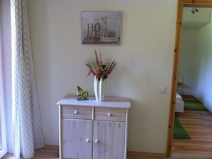 A room with a white cabinet, a framed picture on the wall, and a green mat on the floor. - A light-filled, modern vacation home in the Nordheide (Fintel)