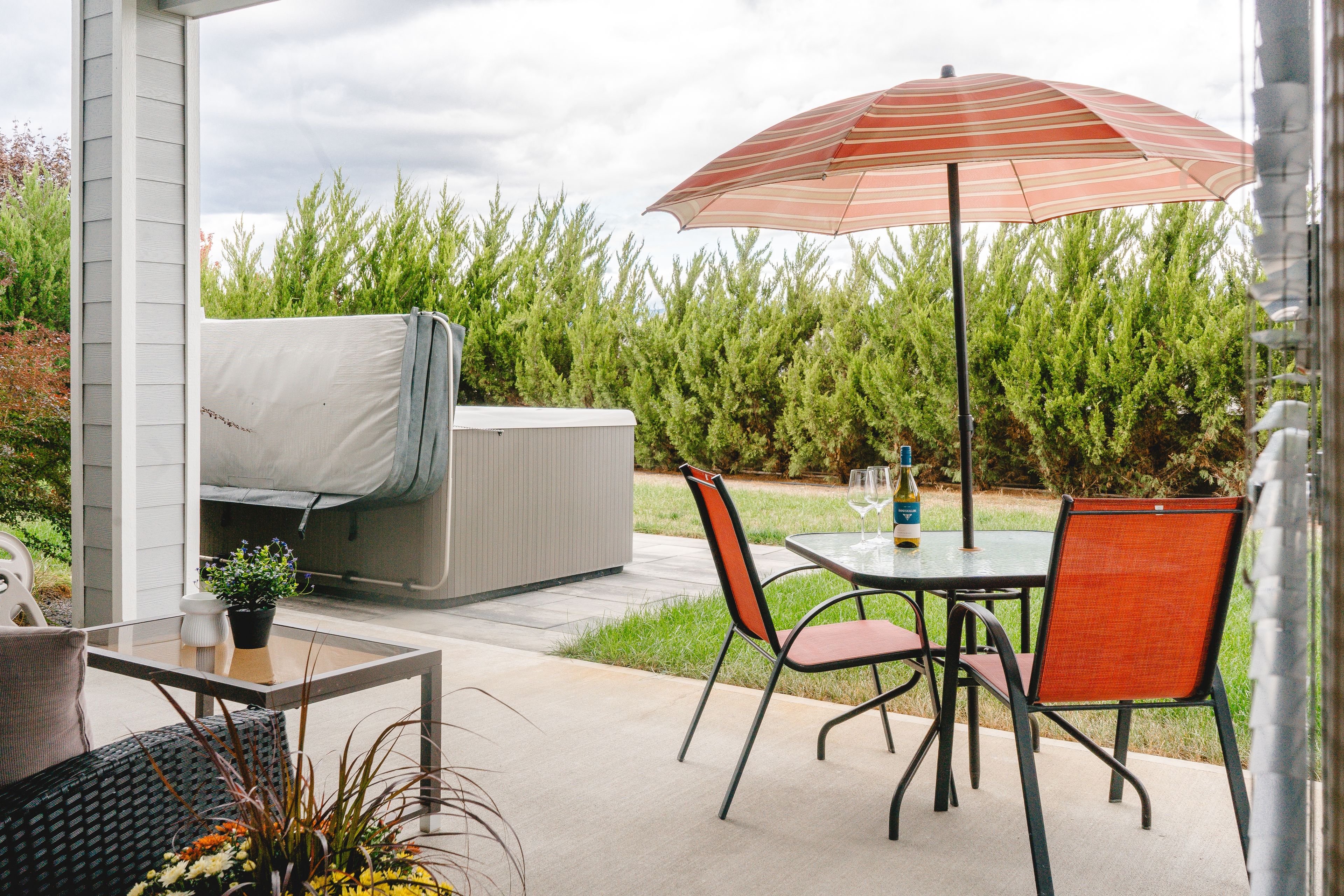 An outdoor patio with a table, chairs, a grill, and an umbrella.