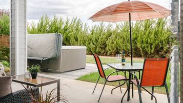 An outdoor patio with a table, chairs, a grill, and an umbrella.