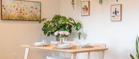 A dining area with a wooden table set for four, surrounded by cushioned chairs.