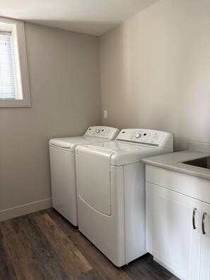 A laundry room with two front-loading washing machines and a built-in sink.
