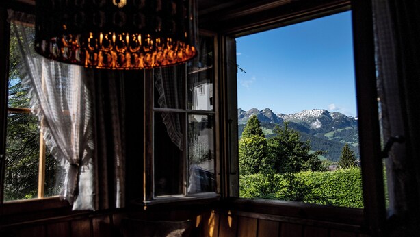 A room with a large window offering a view of snow-capped mountains and a forested valley.