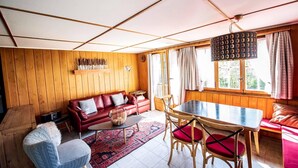 A cozy living room with a red sofa, a coffee table, and a dining area with a table and chairs.